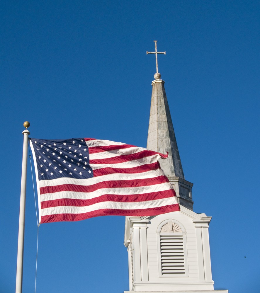American flag and church steeple against very clear blue sky